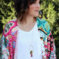 Alex is wearing the Memory Flower Diamond Hoop Charm Necklace -long  gold necklace using pink flowers with charms dangling >